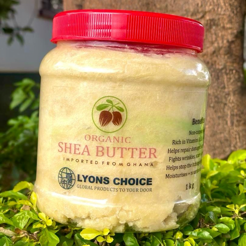 Organic Shea Butter is a product listed on Lyons Choice wocommece store in page Exports. The packaging is large round transparent container containing creamy shea butter with red a transparent label and name of the product written in red color on it with other details in black color. The cap of the container is also red in colors. The product is featuring a natural background of green grasses and leaves.